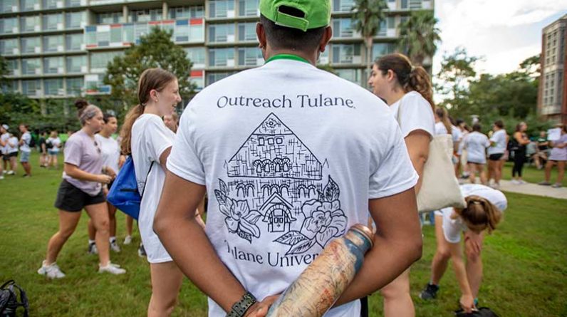 Akhil Chandran, a graduate student in the School of Public Health and Tropical Medicine chats with other Outreach volunteers as they wait to board buses that will take them to service partner locations throughout the New Orleans metro area.