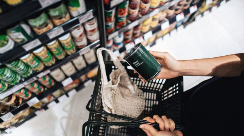 A woman checks the nutrition label on a can of baked beans at the grocery store
